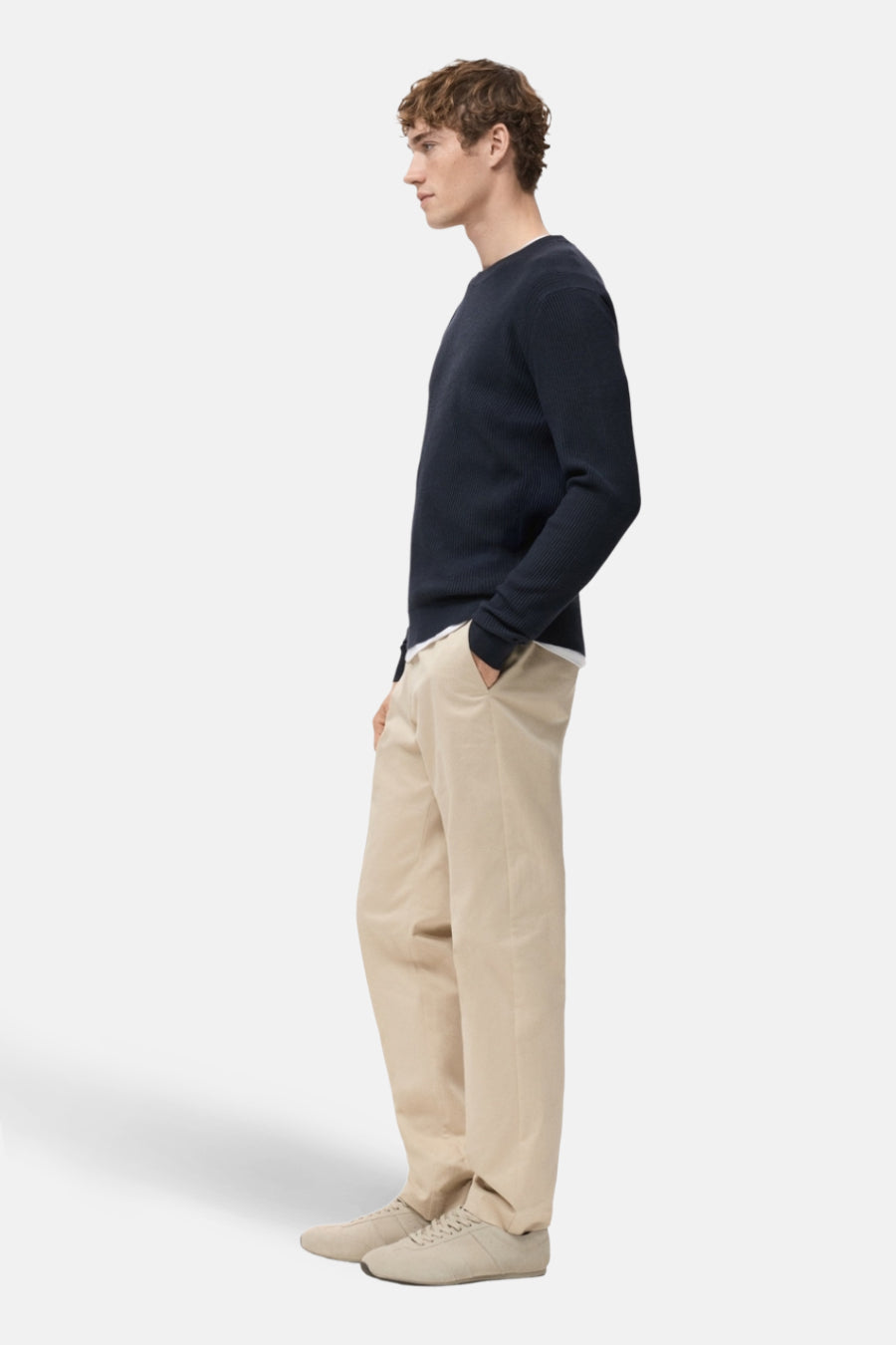 Blauwe trui met ronde hals van MANGO, gedragen met een beige broek en bijpassende sportschoenen, zijwaarts bekeken.