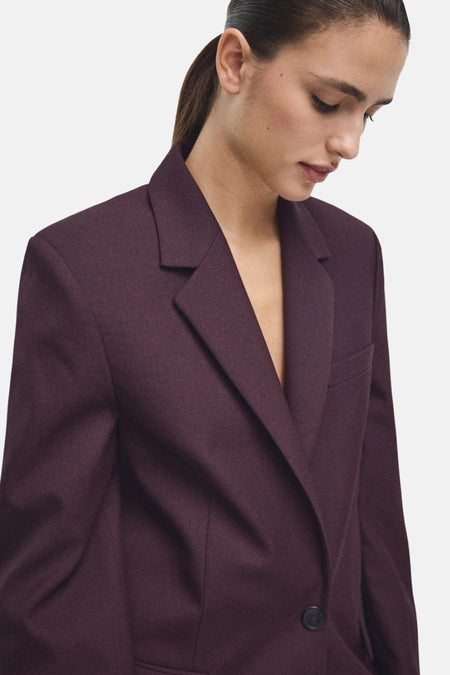 Blazer bordeaux de MANGO, à revers crantés et coupe ajustée portée par un modèle.
