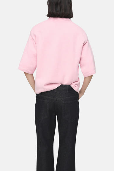 Pull rose à col rond de MANGO, porté avec un jean noir, vue de dos.
