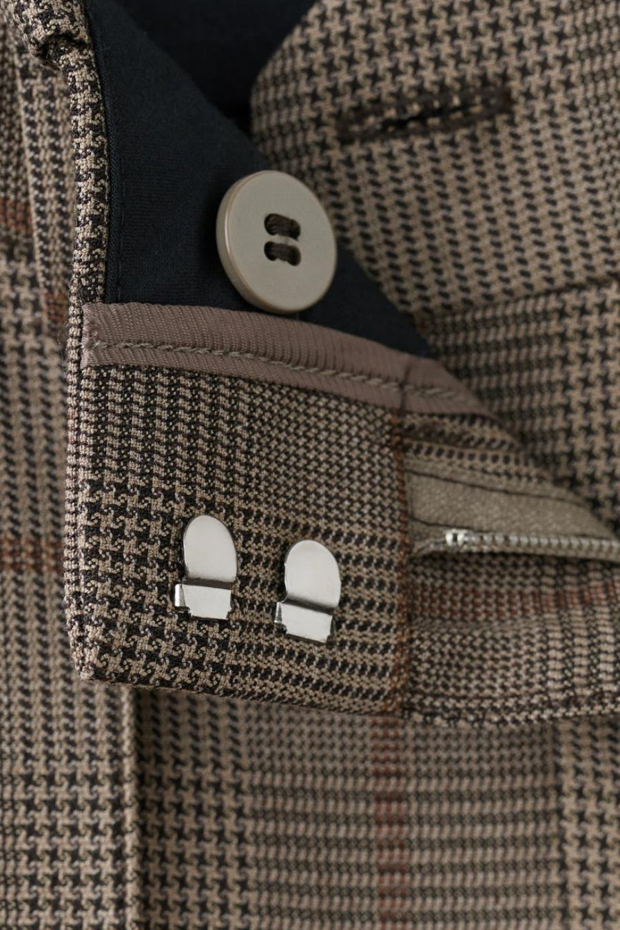 Pantalon brun à motif pied-de-poule de MANGO, avec boutons et fermetures métalliques argentées.