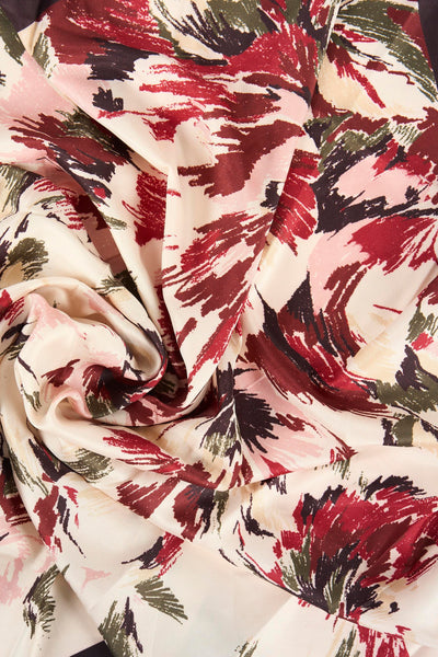 Foulard multicolore de MANGO avec motif floral abstrait dans les tons de rouge, rose, marron et vert sur fond crème.
