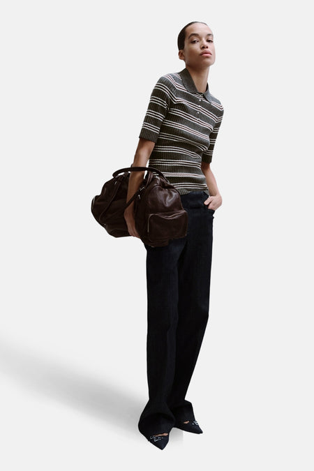 Pull gris à col rond par MANGO, rayures horizontales, porté avec un pantalon foncé et un sac en cuir marron.