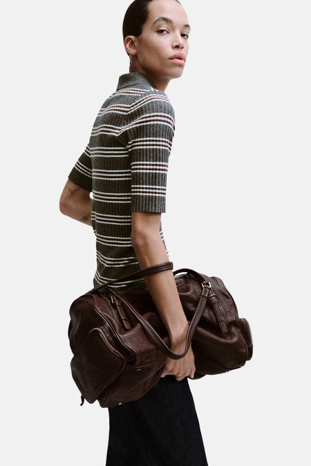 Pull à col rond gris rayé de MANGO, porté avec un grand sac en cuir marron et un jean foncé.
