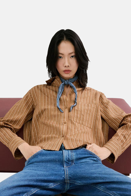 Chemise à manches longues marron by MANGO, rayures verticales blanches et motif à pois, portée avec un foulard bleu et un jean.
