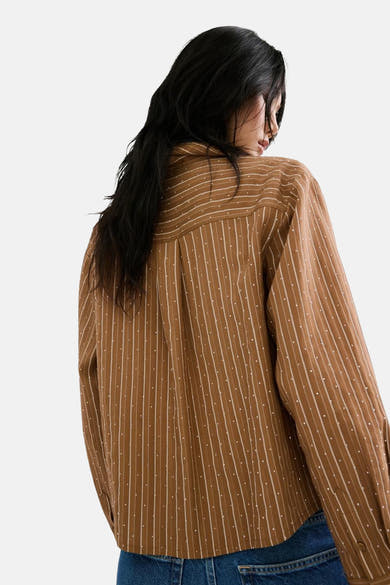 Chemise marron à rayures verticales de MANGO, avec petits pois décoratifs, manches longues et denim visible à la taille.