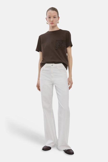 T-shirt brun à manches courtes de MANGO, avec une poche ornée de dentelle, porté avec un jean blanc.
