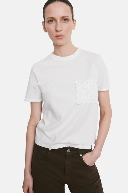 T-shirt blanc à manches courtes de MANGO, avec une poche en dentelle sur la poitrine.