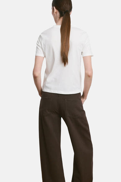 T-shirt blanc de MANGO, porté avec un pantalon marron ample, vue de dos.