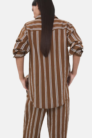 Chemise à manches longues brune rayée de MANGO, avec des rayures verticales blanches et une coupe décontractée.