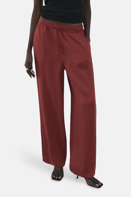 Pantalon brun par MANGO, avec cordon de serrage et coupe ample, porté avec un haut noir et des sandales à talons.