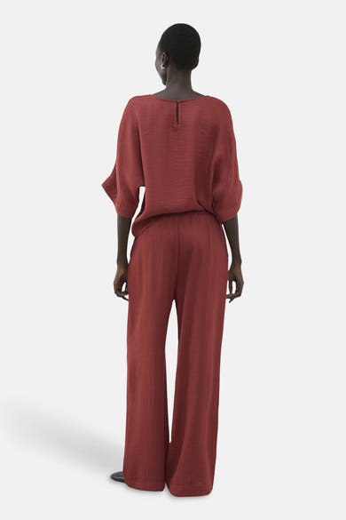 Pantalon brun de MANGO, coupe ample, tissu texturé, porté avec un haut assorti, vue de dos.
