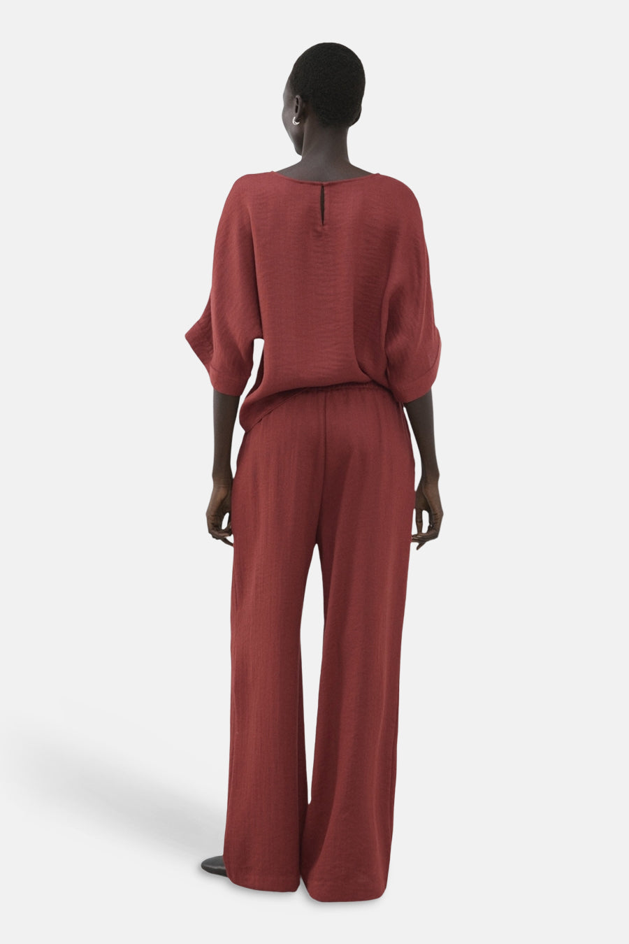 Pantalon brun de MANGO, coupe ample, tissu texturé, porté avec un haut assorti, vue de dos.
