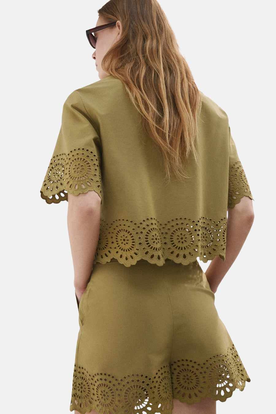 Blouse kaki à manches courtes de MANGO avec broderie anglaise et bords festonnés, portée avec short assorti, vue de dos.