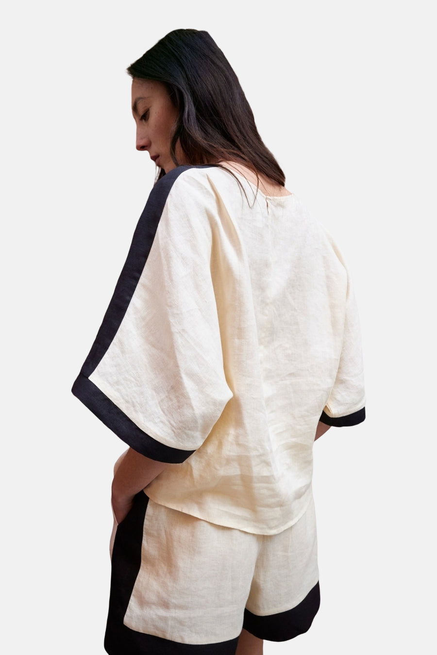 Chemisier à manches courtes crème de MANGO, avec bordure noire aux manches et aux épaules, porté avec un short assorti.
