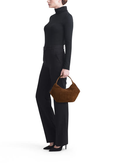 Sac à main brun en daim de MANGO, de forme géométrique, porté par une mannequin en tenue noire.