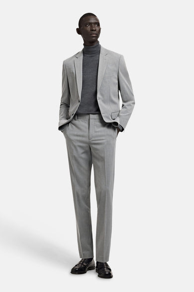 Grijze blazer van MANGO, gedragen met een grijze coltrui en een bijpassende pantalon.