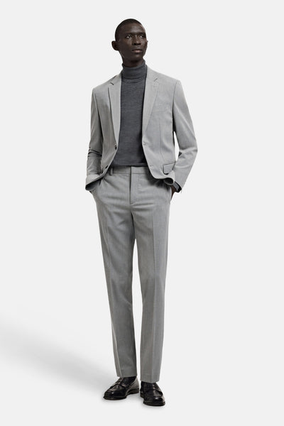 Grijze blazer van MANGO, gedragen met een grijze coltrui en een bijpassende pantalon.