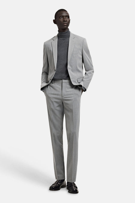 Blazer gris de MANGO, porté avec un col roulé gris et un pantalon de costume assorti.