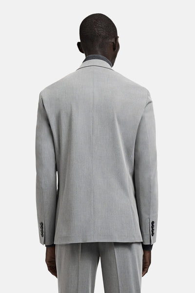 Grijze blazer van MANGO, van achteren gezien, met knopen aan de mouwen en gedragen over een donkergrijze coltrui.
