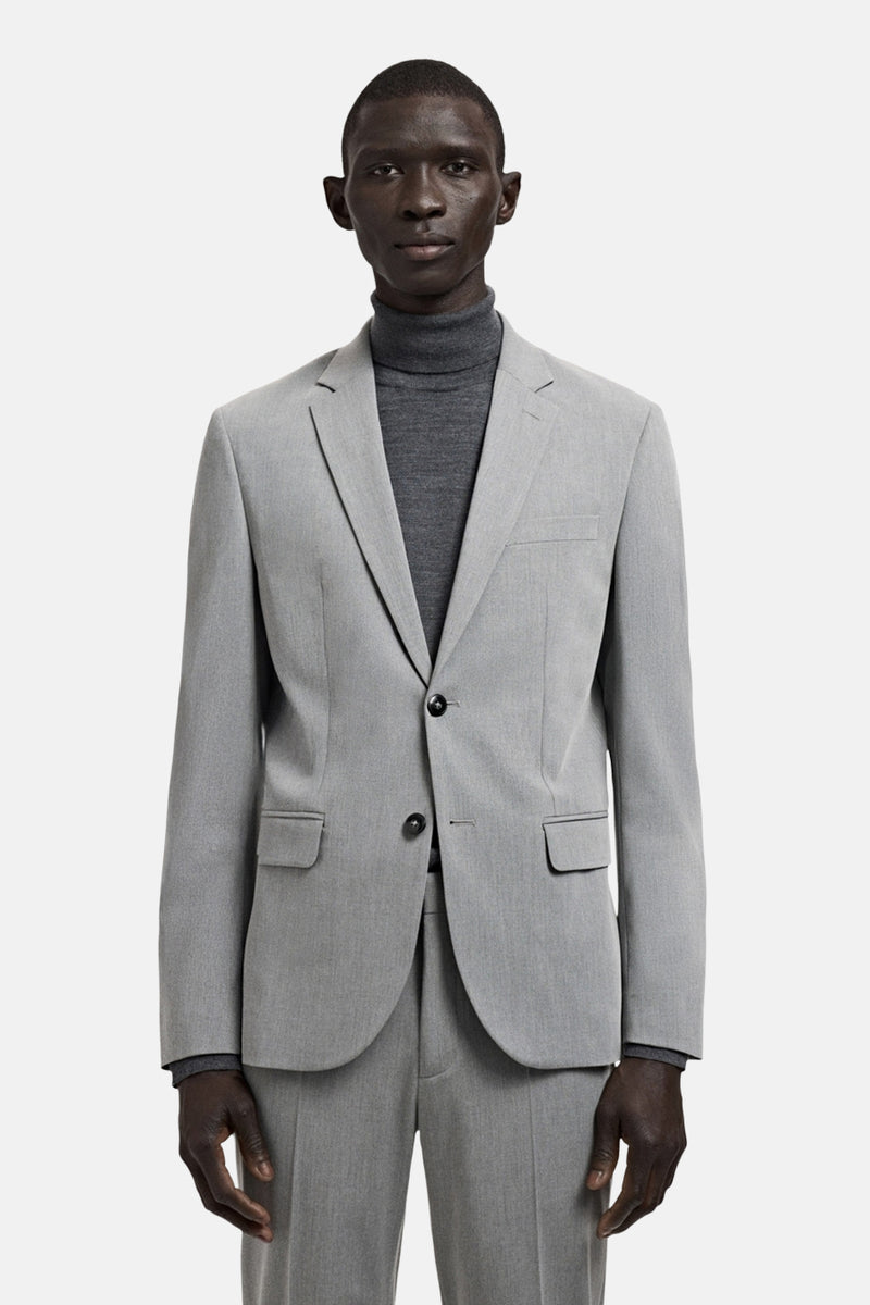 Grijze blazer van MANGO, gedragen met een ton-sur-ton coltrui, met een knoopsgat met vier knopen.