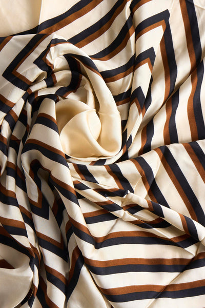 Multikleuren sjaal van MANGO met geometrisch patroon van zwarte en bruine strepen op een geplisseerde beige achtergrond.