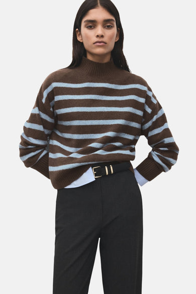 Multikleuren rondehals trui van MANGO, met bruine en lichtblauwe horizontale strepen, gedragen met een zwarte broek.
