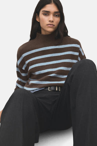 Pull à col rond marron rayé by MANGO avec des rayures bleu clair, porté avec un pantalon noir et une ceinture en cuir noir.