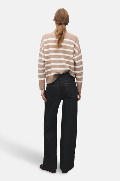 Pull à col rond beige de MANGO, à rayures horizontales, porté avec un jean ample foncé.