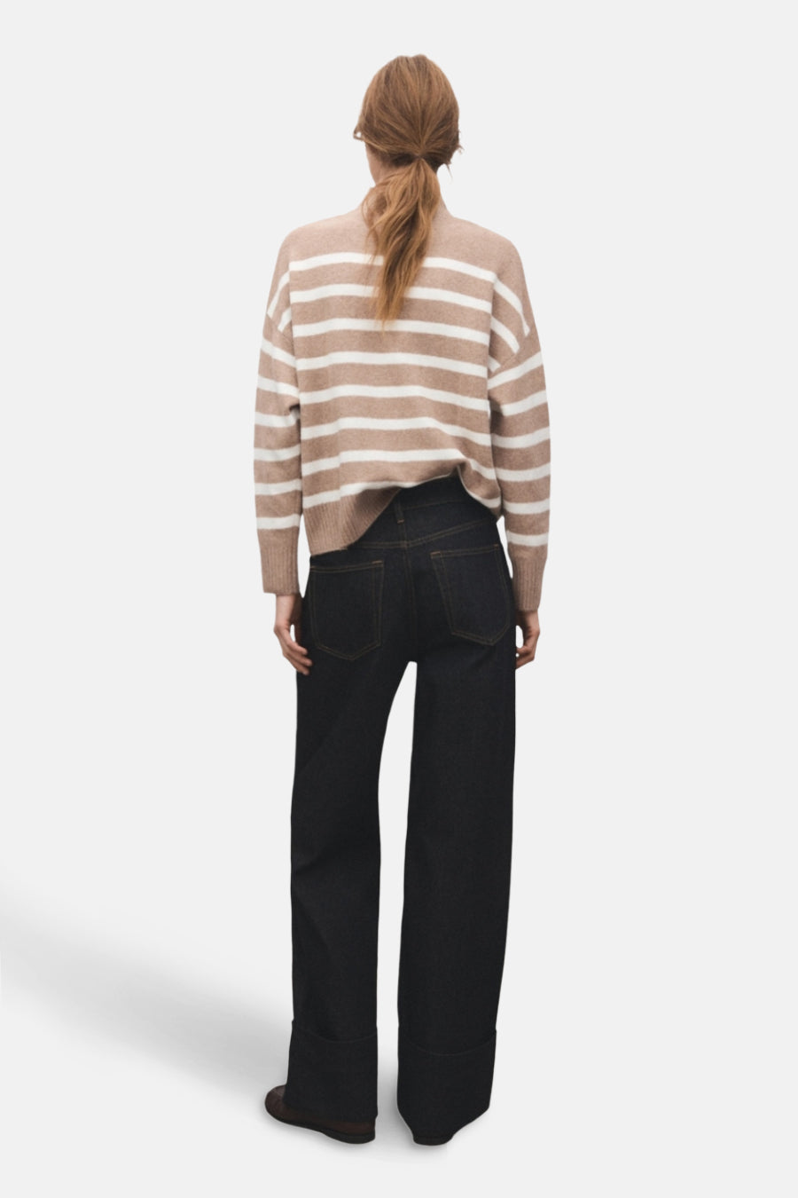 Pull à col rond beige de MANGO, à rayures horizontales, porté avec un jean ample foncé.