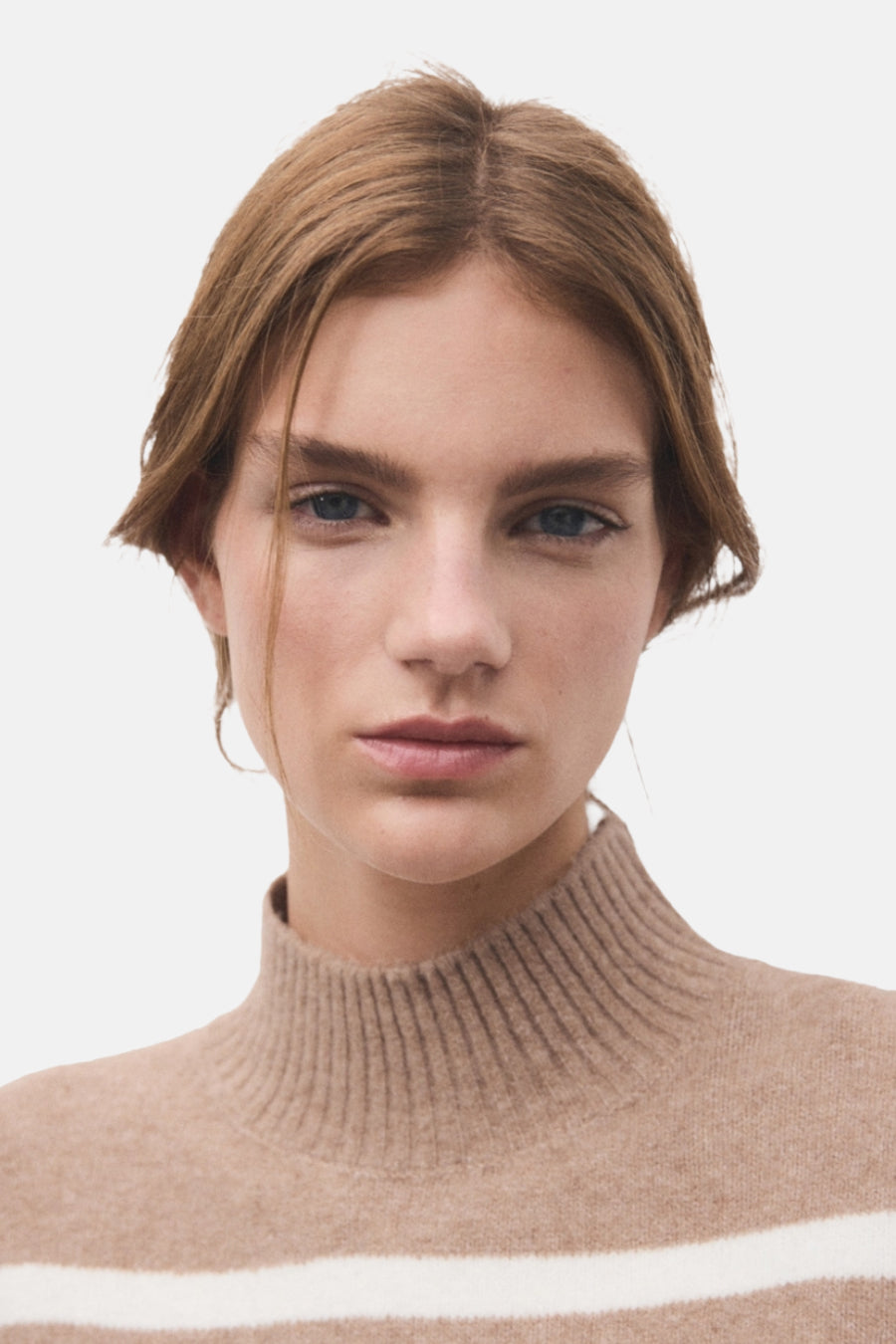 Pull à col rond beige de MANGO, avec une rayure blanche horizontale et une texture côtelée au niveau du col.