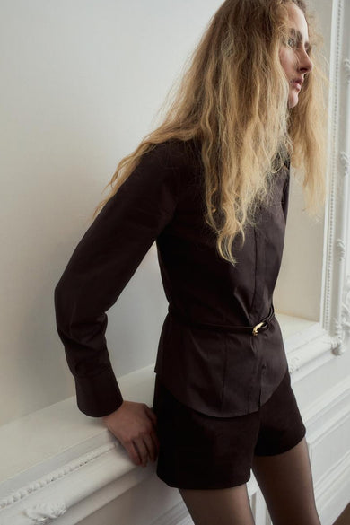 Chemise à manches longues brune de MANGO, avec ceinture fine à boucle dorée et tissu lisse.