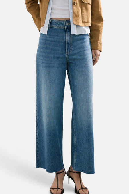 Jean large bleu moyen de MANGO, avec ourlets bruts et coupe ample.