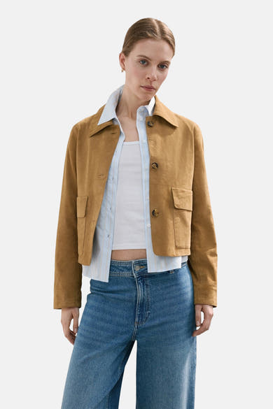 Wijde spijkerbroek in middieblauw denim van MANGO, gedragen met een bruin jasje en een witte top.