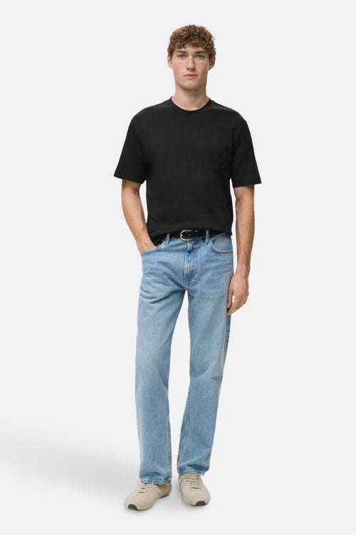 T-shirt noir à manches courtes de MANGO, porté avec un jean bleu et des chaussures de sport beiges.