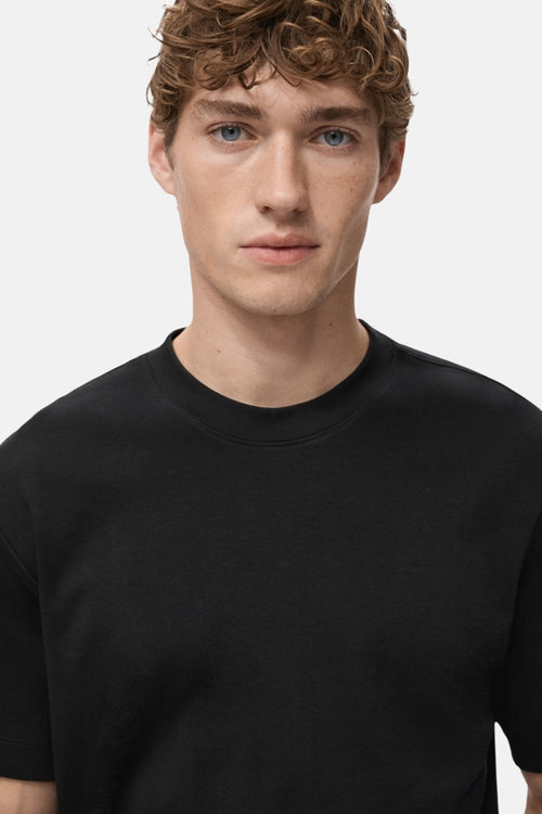 T-shirt à manches courtes noir de MANGO, porté par un homme aux cheveux bouclés et aux yeux bleus.
