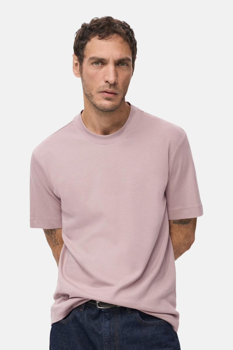 T-shirt rose à manches courtes de MANGO, porté avec un jean bleu foncé et une ceinture noire.