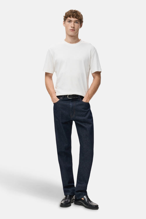 T-shirt blanc à manches courtes de MANGO, porté avec un jean bleu foncé et des mocassins noirs.