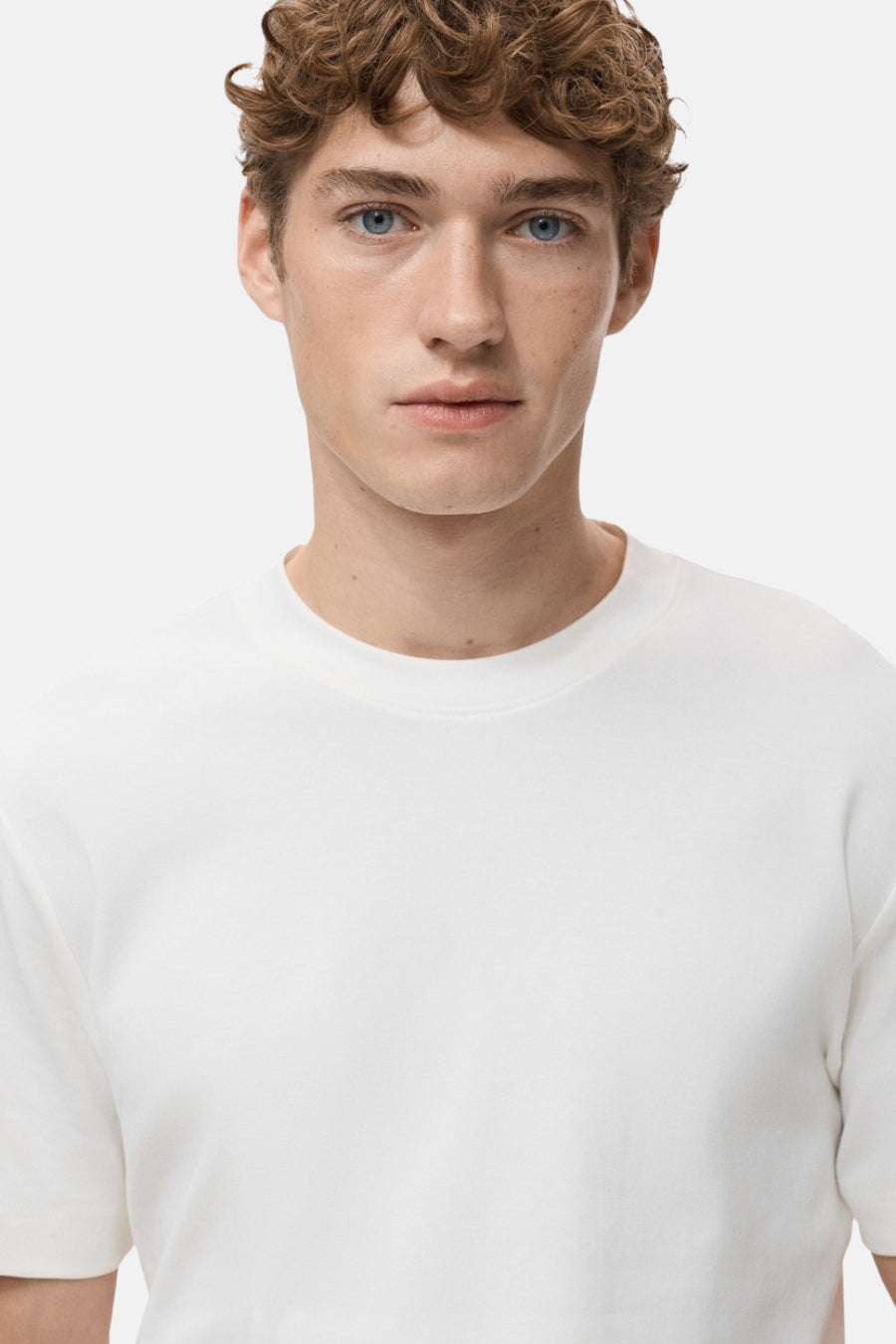 Witte t-shirt met korte mouwen van MANGO, gedragen door een man met blonde gekrulde haar en blauwe ogen.