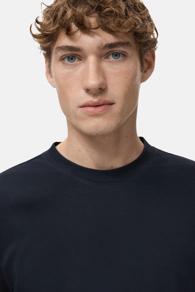 T-shirt bleu à manches courtes de MANGO, uni, porté par un homme aux yeux bleus et aux cheveux bouclés.