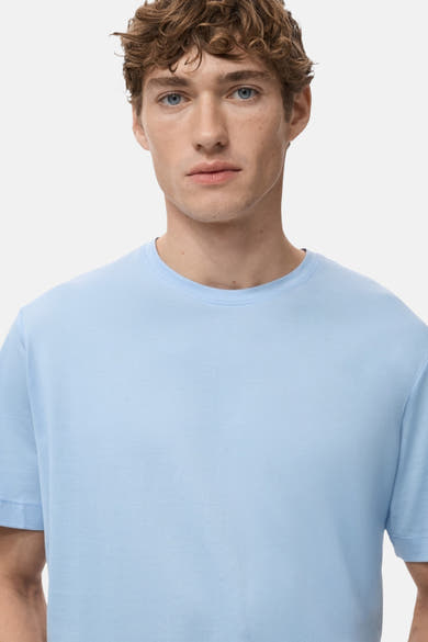 T-shirt bleu à manches courtes de MANGO, porté par un homme aux cheveux bouclés.
