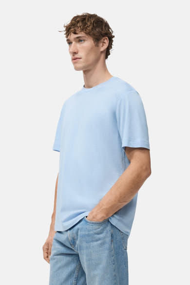 T-shirt à manches courtes bleu de MANGO, porté avec un jean bleu clair, en vue de côté.