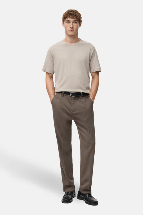 T-shirt à manches courtes beige de MANGO, porté avec un pantalon marron et des chaussures noires.