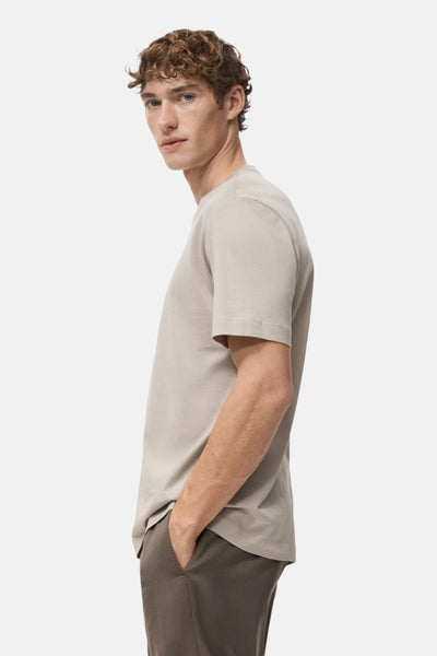 T-shirt beige à manches courtes de MANGO, porté avec un pantalon marron, vue de côté.
