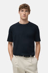 T-shirt à manches courtes bleu de MANGO, porté avec un pantalon clair et une ceinture noire.