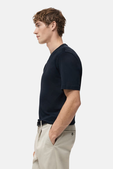 T-shirt bleu à manches courtes de MANGO, porté avec un pantalon beige et une ceinture noire, vue de profil.