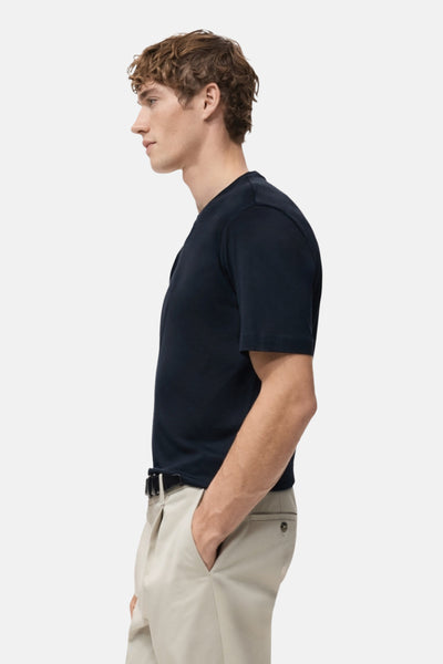 T-shirt bleu à manches courtes de MANGO, porté avec un pantalon beige et une ceinture noire, vue de profil.