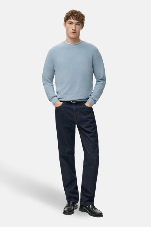 Pull à col rond bleu de MANGO, porté avec un jean foncé et des mocassins noirs.