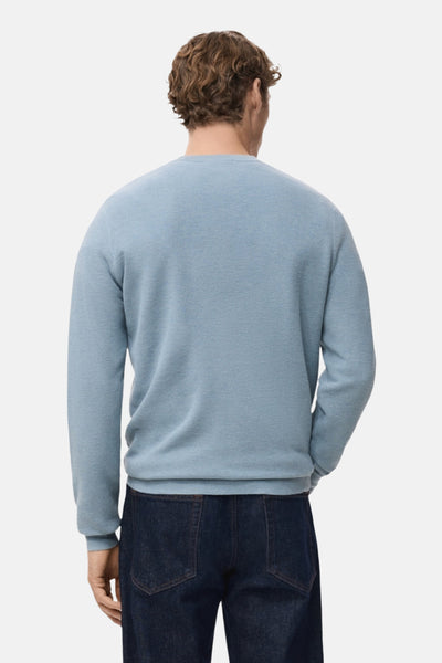 Pull à col rond bleu de MANGO, vu de dos, porté avec un jean en denim foncé.