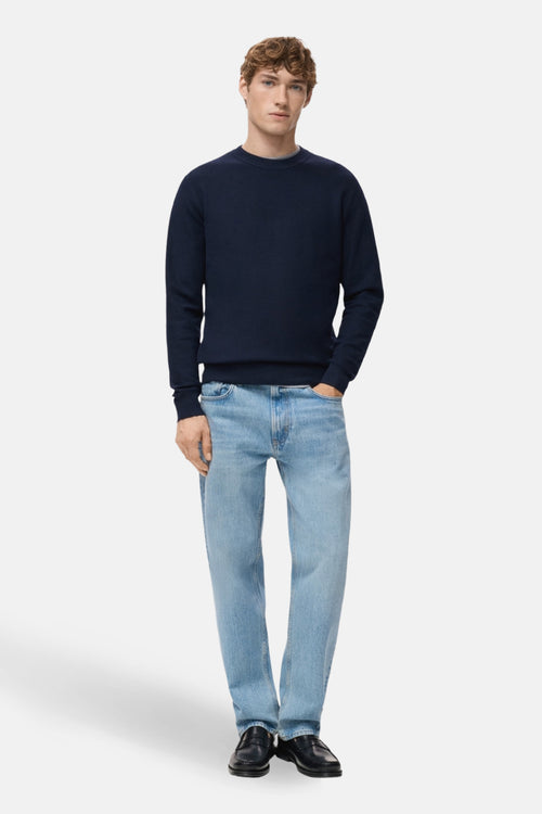Pull à col rond bleu de MANGO, porté avec un jean décontracté et des mocassins noirs.