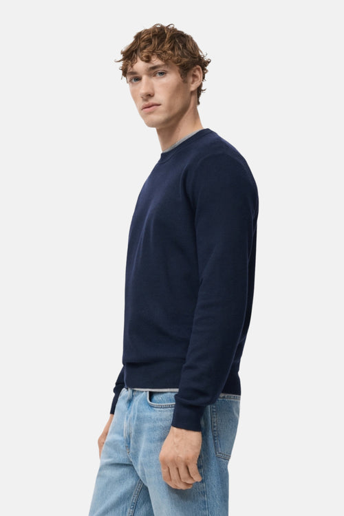 Pull à col rond bleu de MANGO, porté avec un jean bleu clair, vue de côté.